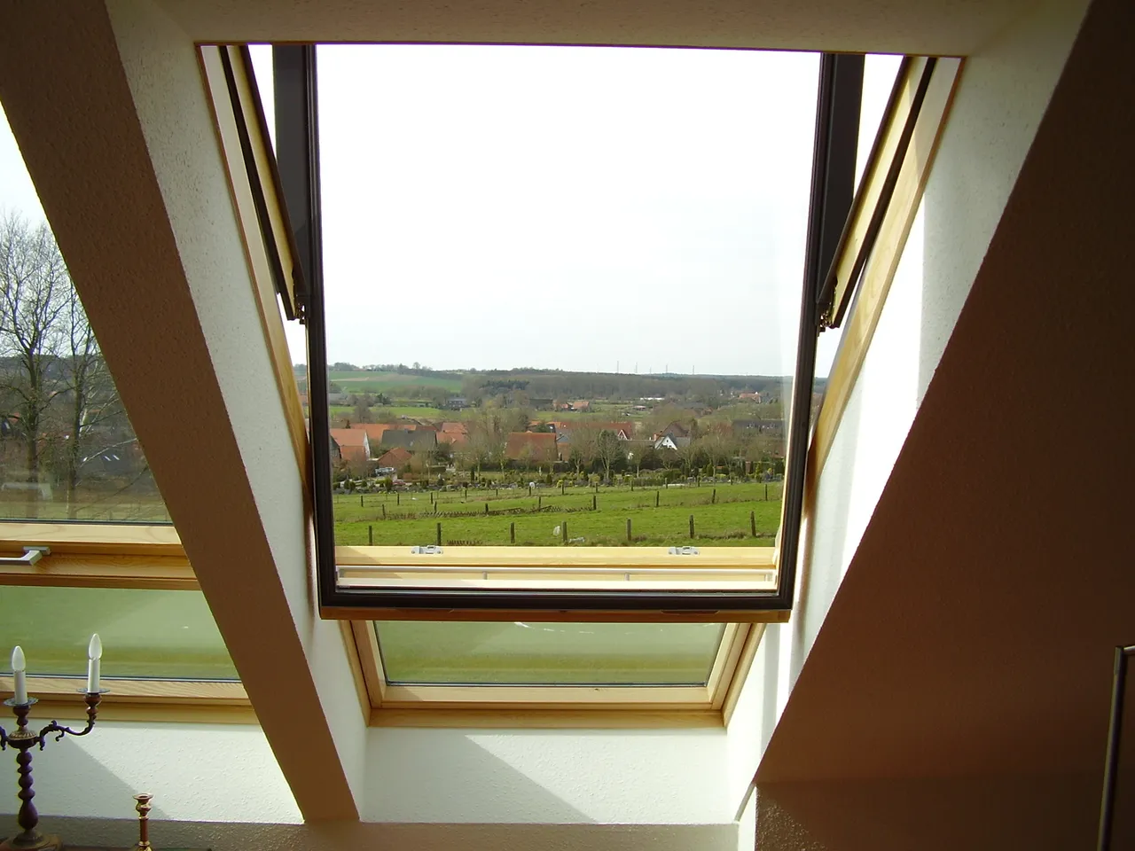 An open timber roof window bringing daylight into a sloped attic room